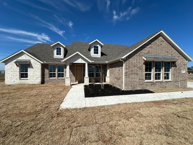 view of front facade featuring a shingled roof and brick siding