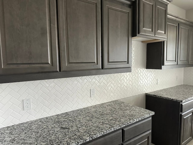 kitchen featuring tasteful backsplash, dark brown cabinets, and dark stone countertops