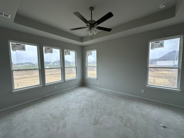 unfurnished room with ceiling fan and a tray ceiling