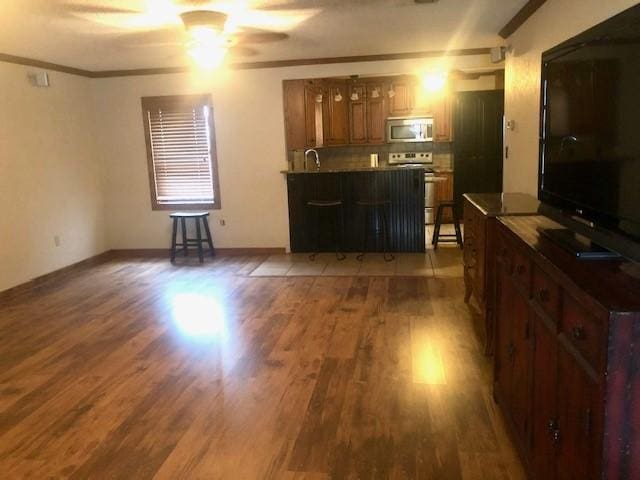 living room featuring sink, ornamental molding, dark hardwood / wood-style floors, and ceiling fan