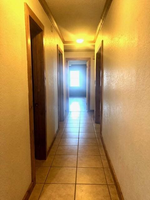 hall with crown molding and light tile patterned floors