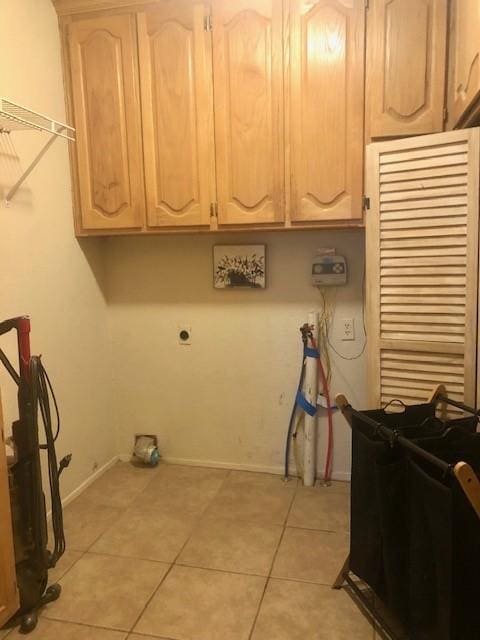 laundry room with light tile patterned floors, cabinets, and hookup for an electric dryer