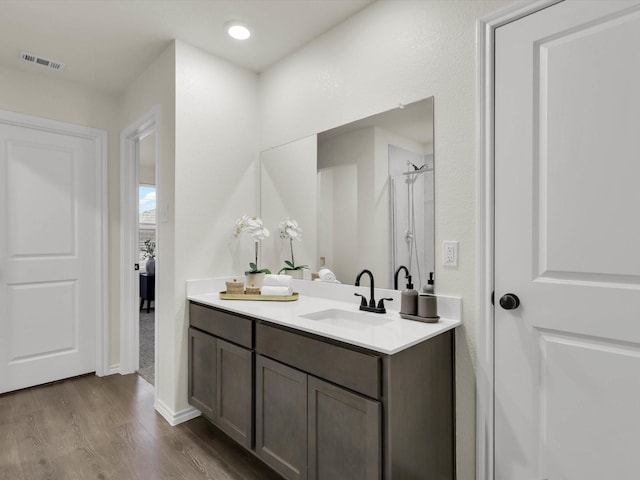 bathroom with hardwood / wood-style flooring, vanity, and walk in shower