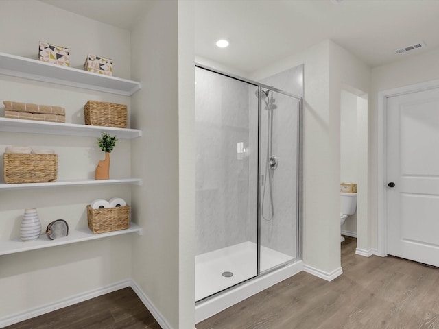 bathroom featuring wood-type flooring, a shower with door, and toilet