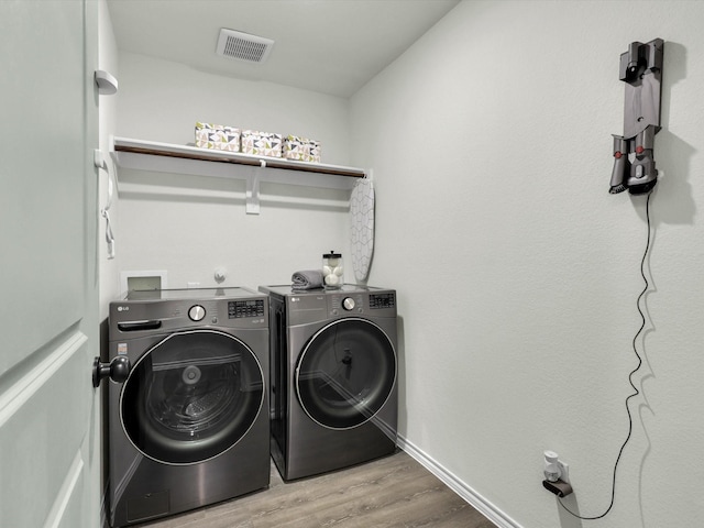 clothes washing area with hardwood / wood-style floors and washing machine and dryer