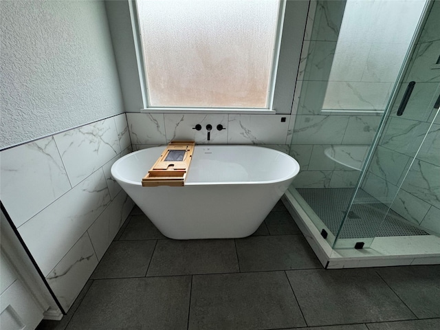 bathroom with tile walls and independent shower and bath