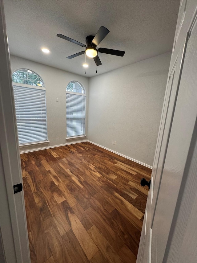 unfurnished room featuring dark hardwood / wood-style flooring, ceiling fan, and a textured ceiling