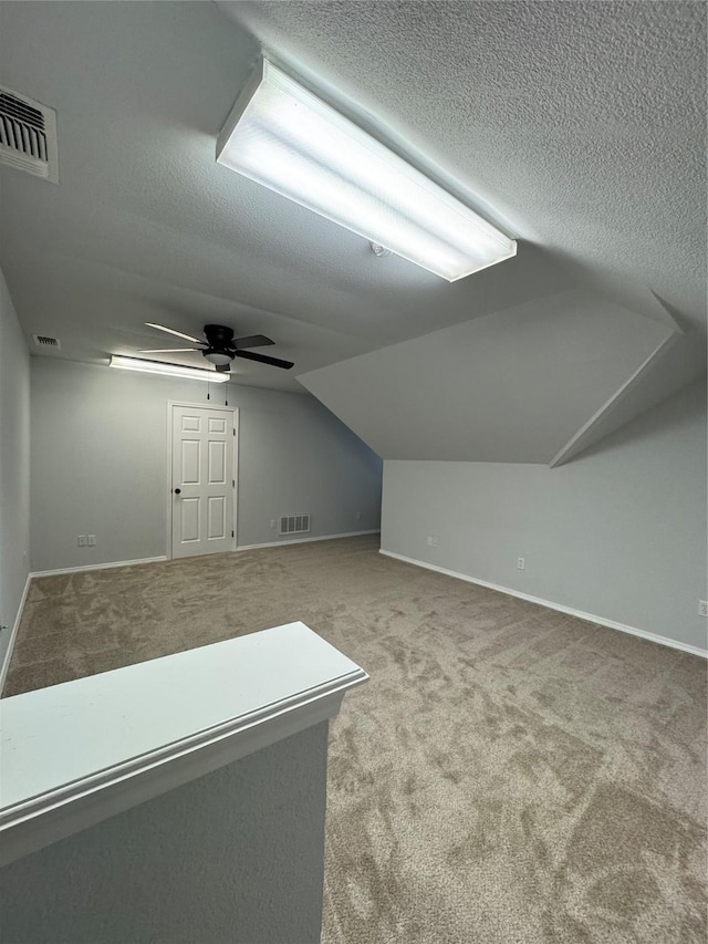 additional living space featuring ceiling fan, lofted ceiling, carpet, and a textured ceiling