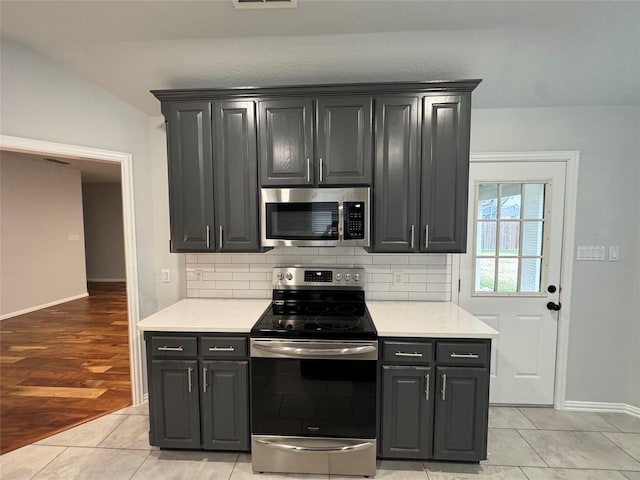 kitchen with tasteful backsplash, lofted ceiling, stainless steel appliances, and light tile patterned flooring