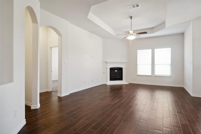 unfurnished living room featuring dark hardwood / wood-style flooring, a raised ceiling, and ceiling fan