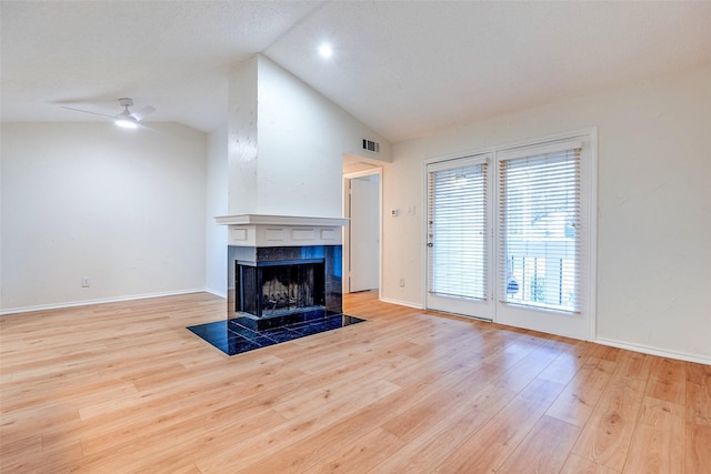 unfurnished living room with ceiling fan, a fireplace, vaulted ceiling, and light wood-type flooring