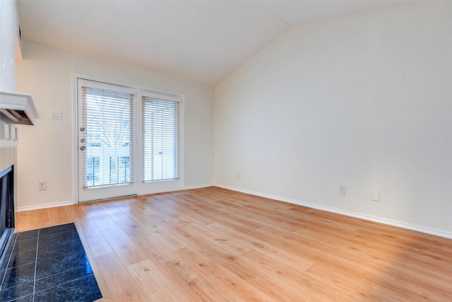 unfurnished living room featuring vaulted ceiling and light hardwood / wood-style flooring