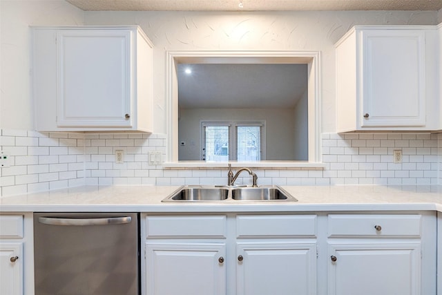 kitchen featuring dishwasher, sink, white cabinets, and backsplash