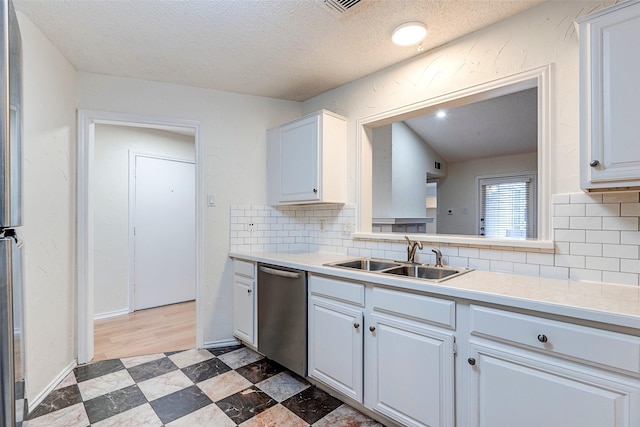 kitchen with sink, white cabinets, backsplash, stainless steel dishwasher, and a textured ceiling