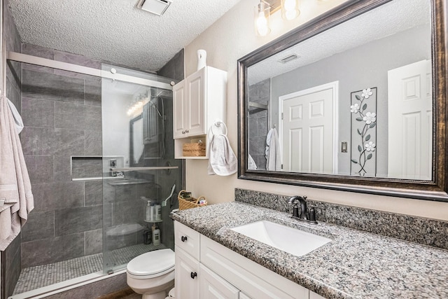 bathroom featuring walk in shower, vanity, toilet, and a textured ceiling