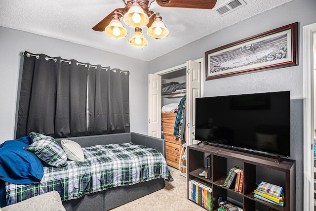 carpeted bedroom featuring ceiling fan and a textured ceiling