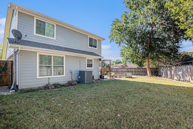 rear view of property with cooling unit and a yard