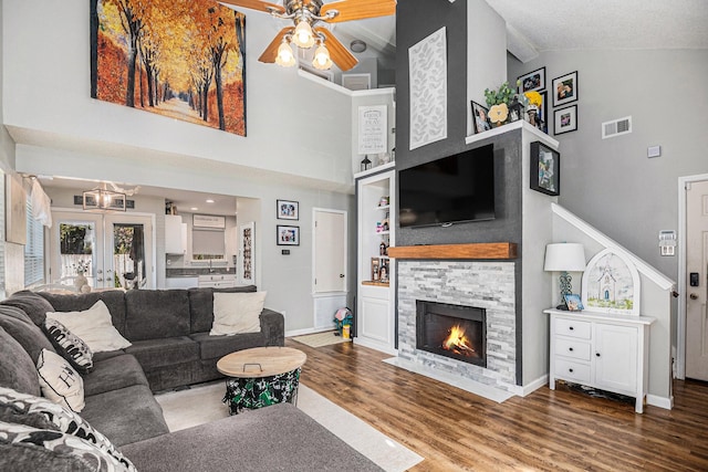 living room with a stone fireplace, high vaulted ceiling, ceiling fan, and hardwood / wood-style flooring