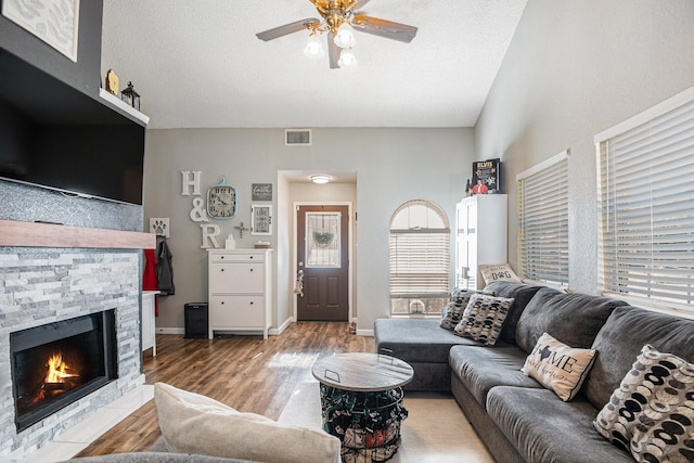 living room featuring hardwood / wood-style flooring, ceiling fan, a textured ceiling, and a fireplace