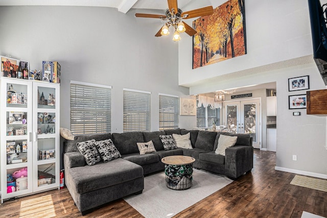 living room with beamed ceiling, a high ceiling, ceiling fan, dark wood-type flooring, and french doors