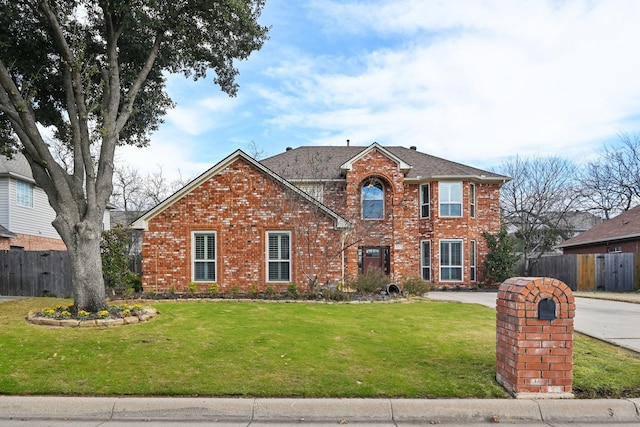 traditional-style house with brick siding, a front lawn, and fence