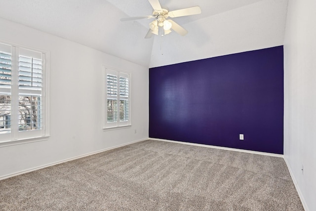 carpeted spare room featuring lofted ceiling, baseboards, a wealth of natural light, and a ceiling fan