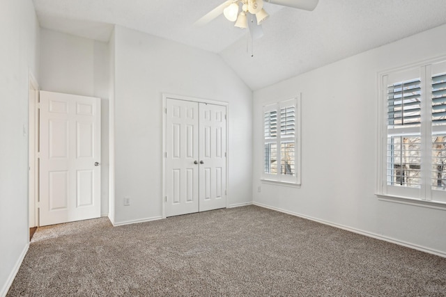 unfurnished bedroom with lofted ceiling, a closet, a ceiling fan, carpet flooring, and baseboards