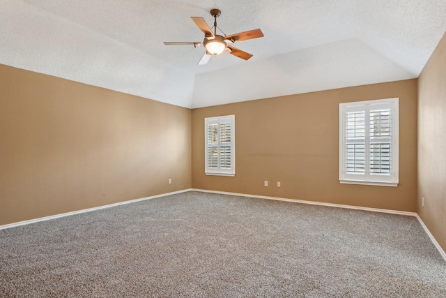 carpeted empty room featuring lofted ceiling, a textured ceiling, baseboards, and a ceiling fan