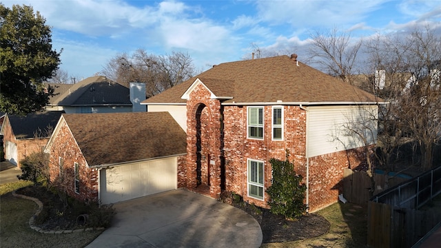 view of front of home with a garage, brick siding, fence, concrete driveway, and roof with shingles