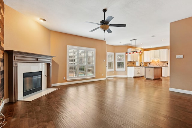 unfurnished living room with dark wood-style flooring, a fireplace, recessed lighting, ceiling fan, and baseboards