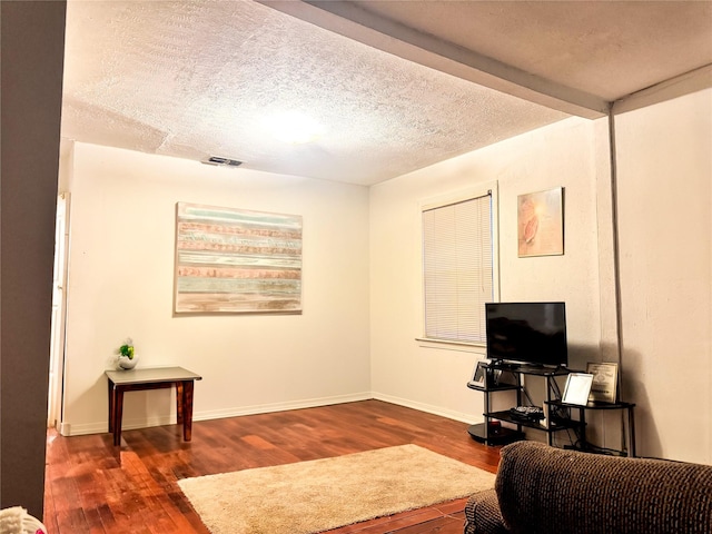 living room with beamed ceiling, dark hardwood / wood-style floors, and a textured ceiling