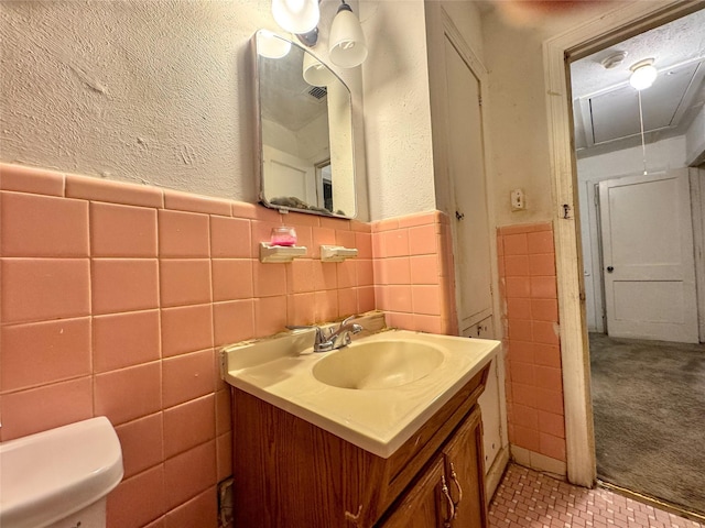 bathroom with vanity, tile walls, and toilet