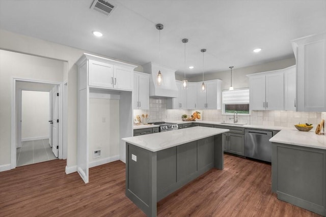 kitchen with white cabinetry, sink, stainless steel appliances, and a center island