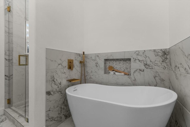 bathroom featuring shower with separate bathtub and tile walls