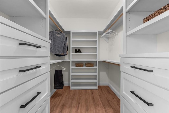 walk in closet with light hardwood / wood-style flooring