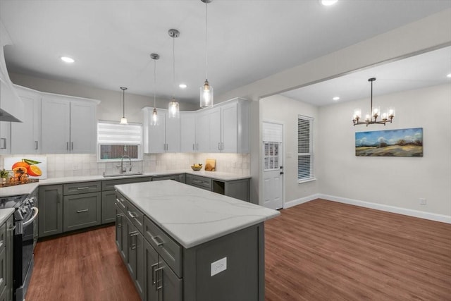 kitchen featuring black electric range oven, sink, white cabinetry, a center island, and hanging light fixtures