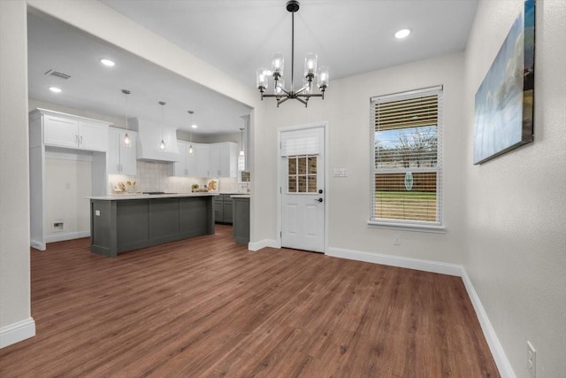 kitchen featuring a center island, decorative backsplash, white cabinets, dark hardwood / wood-style flooring, and decorative light fixtures