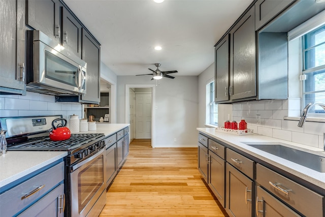 kitchen featuring appliances with stainless steel finishes, sink, ceiling fan, plenty of natural light, and light wood-type flooring