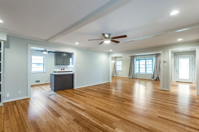 unfurnished living room with ceiling fan, ornamental molding, a healthy amount of sunlight, and light hardwood / wood-style floors