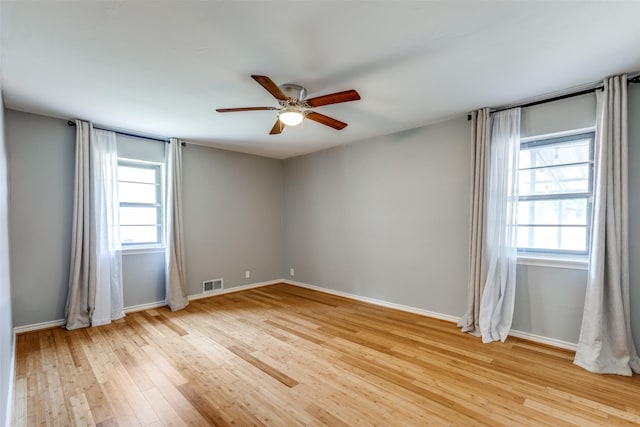 spare room featuring ceiling fan, a healthy amount of sunlight, and light wood-type flooring