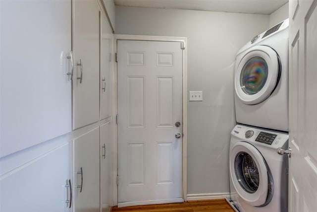 laundry room featuring wood-type flooring and stacked washing maching and dryer