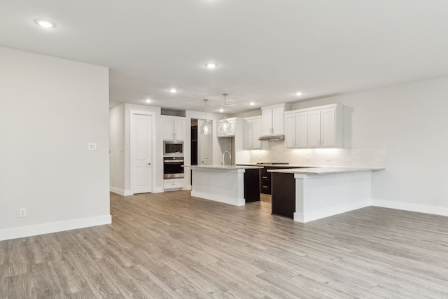 kitchen featuring pendant lighting, white cabinetry, backsplash, a kitchen island with sink, and stainless steel appliances