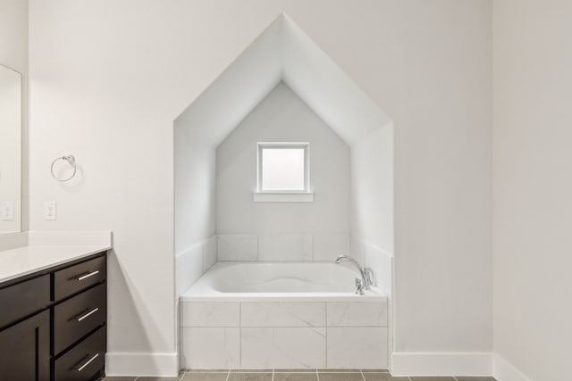 bathroom with lofted ceiling, vanity, and tiled bath