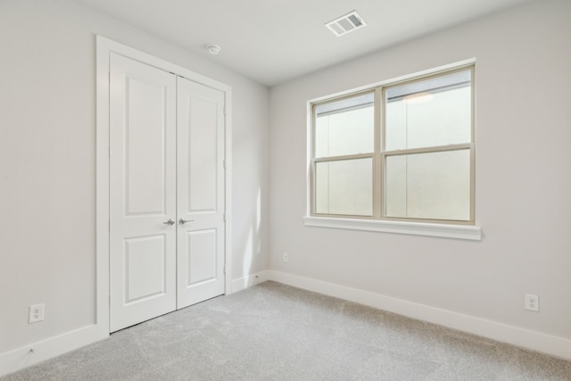 unfurnished bedroom featuring light colored carpet and a closet