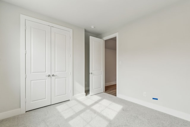 unfurnished bedroom featuring light colored carpet and a closet