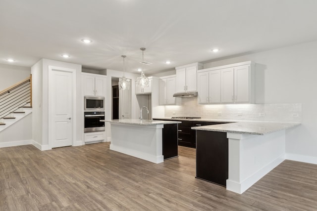 kitchen with sink, white cabinets, hanging light fixtures, a kitchen island with sink, and stainless steel appliances