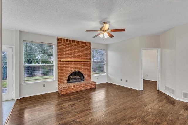 unfurnished living room featuring dark wood-type flooring, a fireplace, a textured ceiling, and ceiling fan