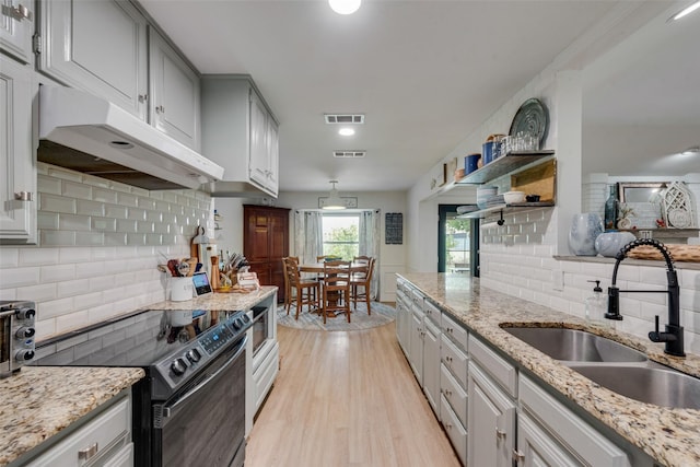 kitchen with sink, light stone counters, electric range, and light wood-type flooring