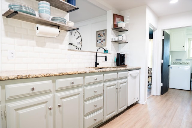 kitchen featuring washer / dryer, sink, white cabinets, decorative backsplash, and light hardwood / wood-style floors