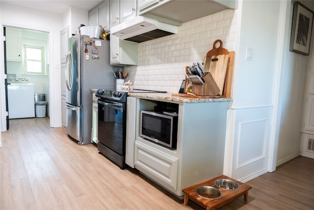 kitchen featuring appliances with stainless steel finishes, tasteful backsplash, light stone counters, washer / dryer, and light wood-type flooring